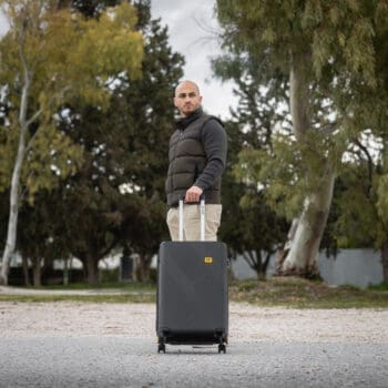 Βαλίτσα μεσαία σκληρή σε μαύρο χρώμα με άνθρωπο να την κρατάει